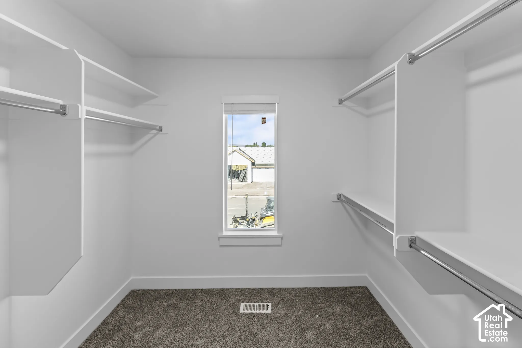 Walk-in closet featuring built-in shelving, chrome hanging rods, a window for natural light, and carpet flooring