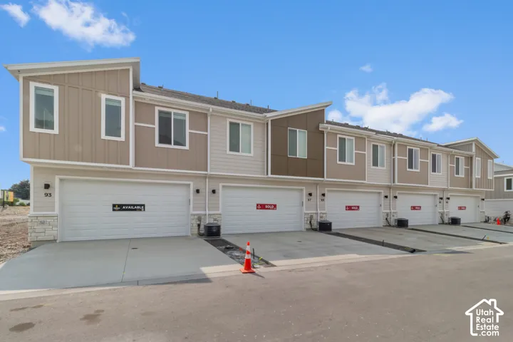 Contemporary townhome exterior with mixed material siding, white trim, and a prominent attached garage