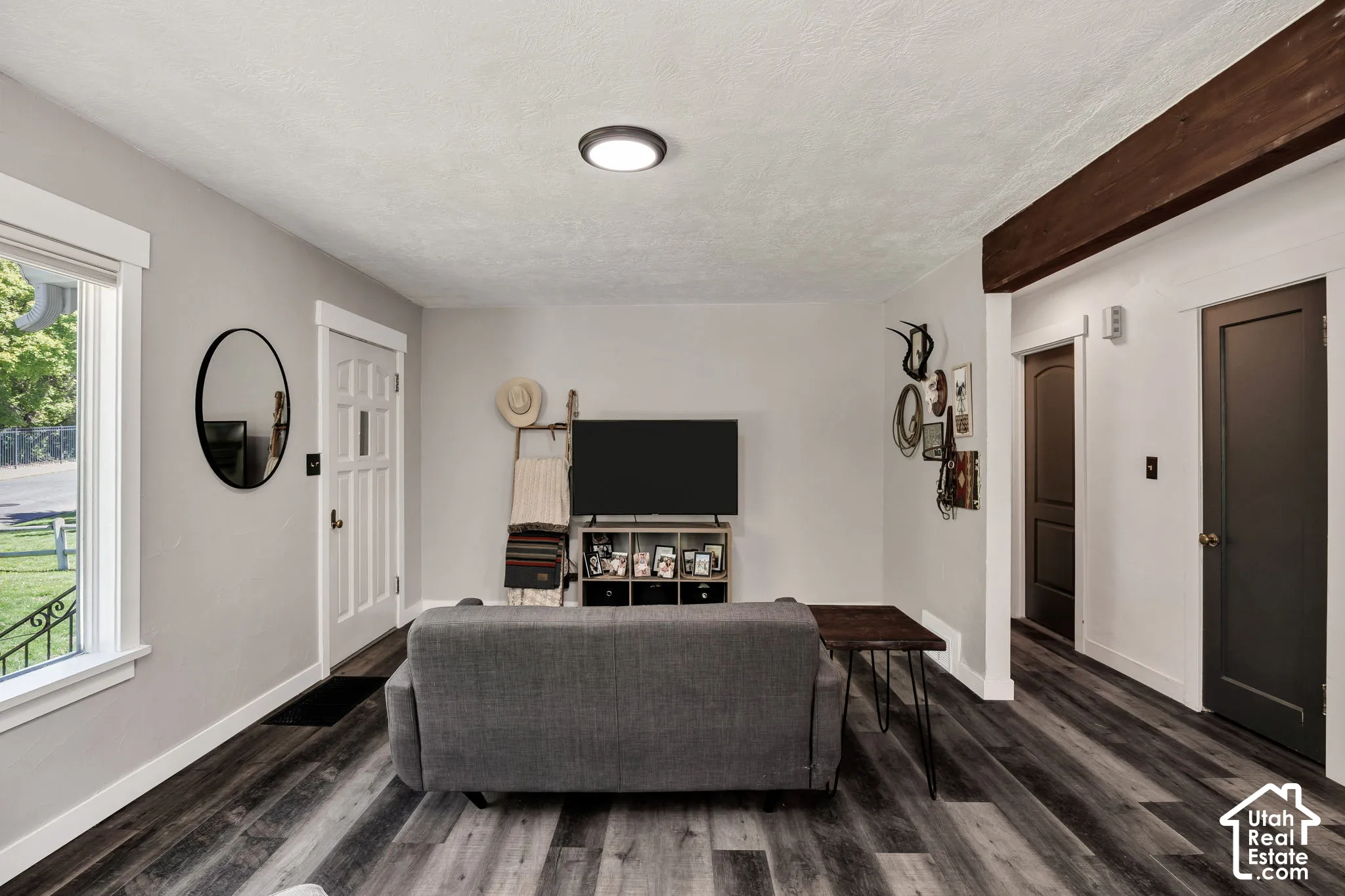 Wood-finish LVP flooring throughout, white trim, and a dark wood beam accent