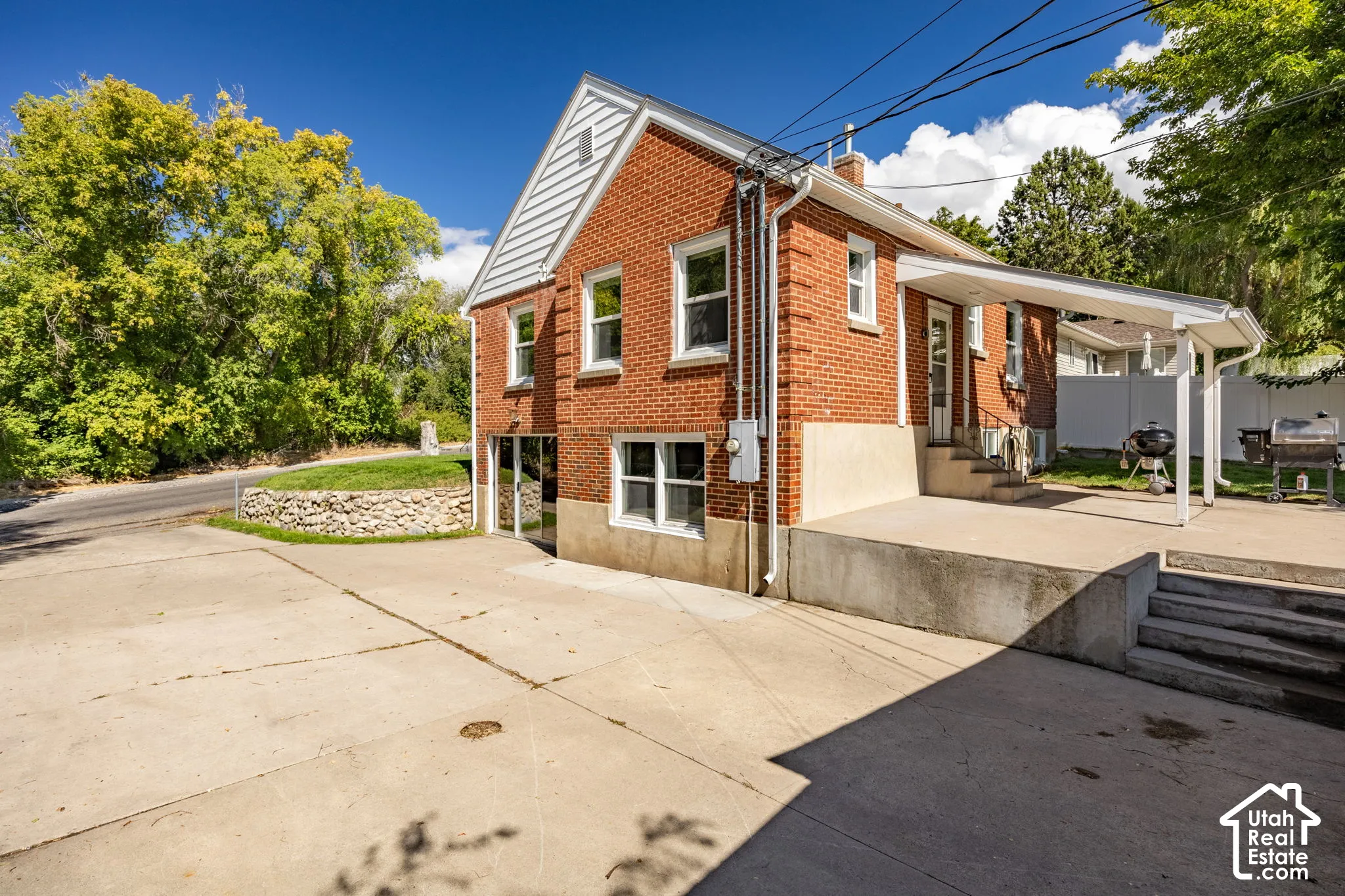 Brick exterior, concrete patio, covered patio area, concrete driveway, stone retaining wall