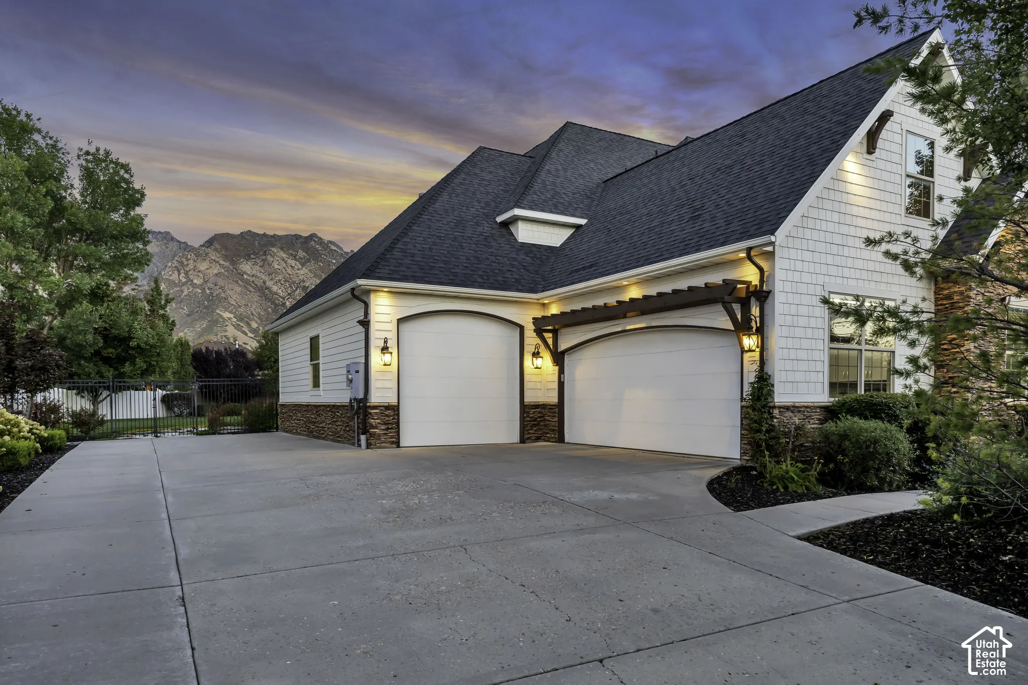 Two-car garage with arched doors, integrated pergola, and exterior lighting