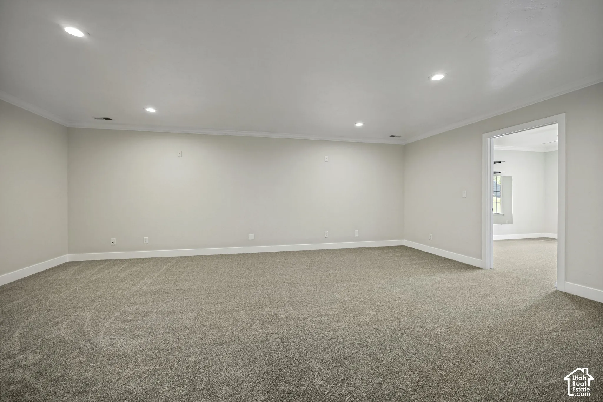 Expansive room featuring recessed lighting, crown molding, light-colored walls, and neutral carpet flooring