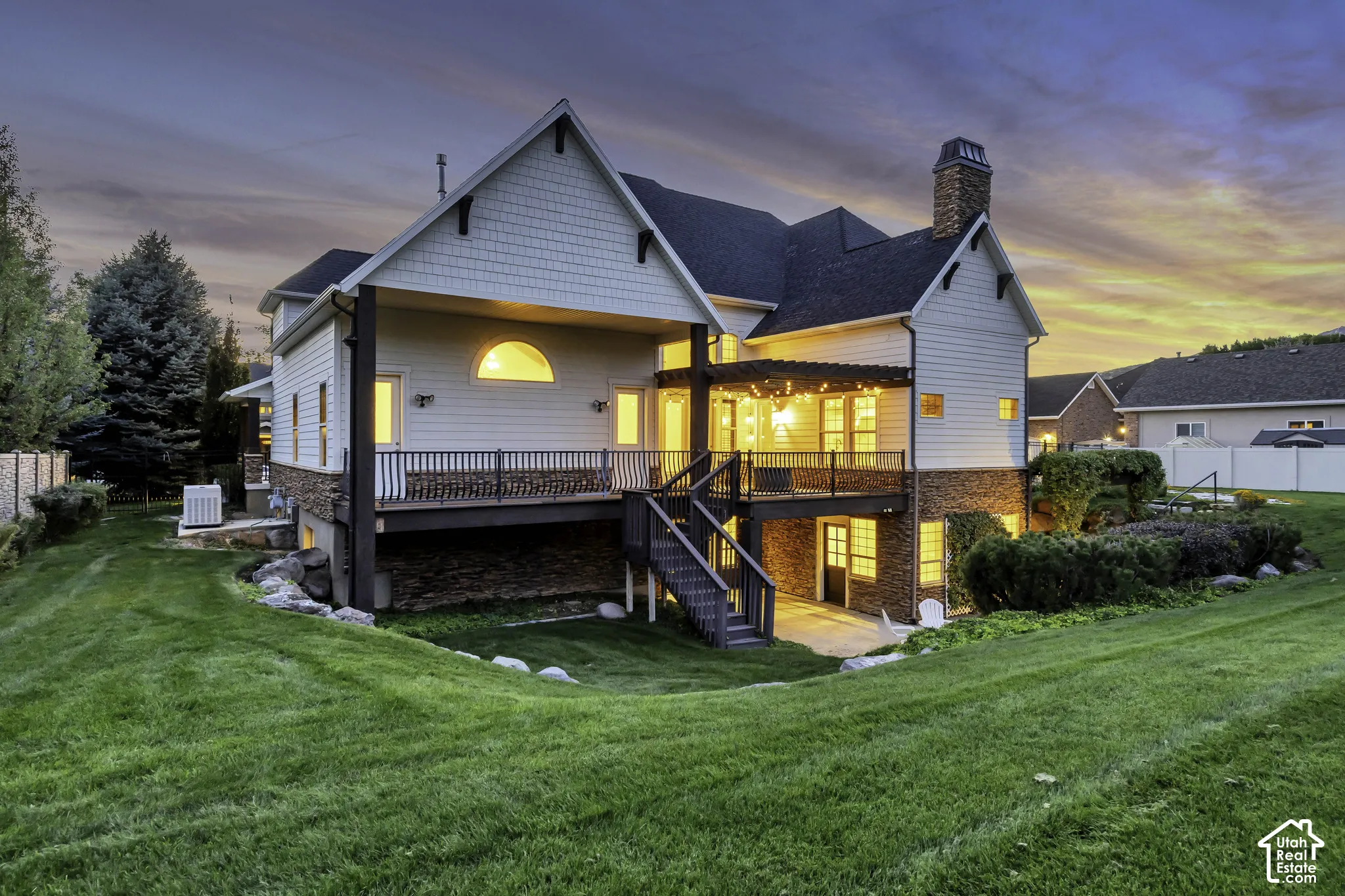 Two-story exterior with horizontal siding and shingle accents, a covered deck, and an expansive lawn