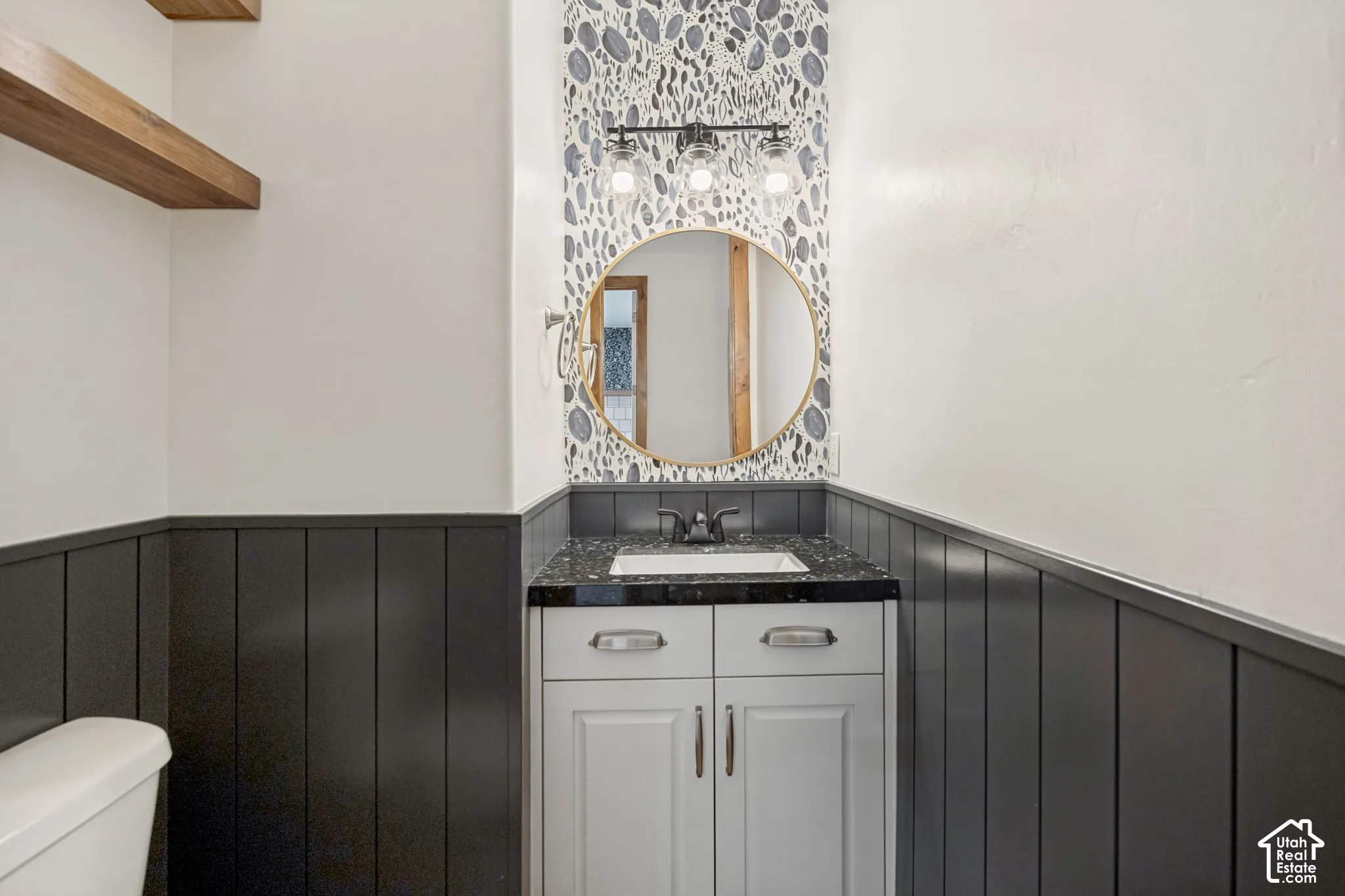 Vanity with integrated sink, dark speckled countertop, and light wood-finish cabinetry