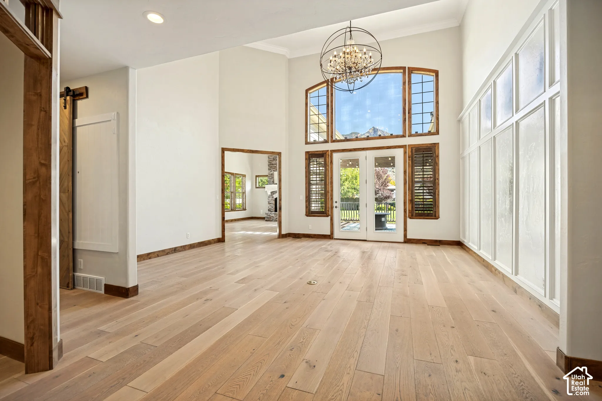 Vaulted ceilings, wood-finish flooring, custom chandelier, and French doors with transom windows