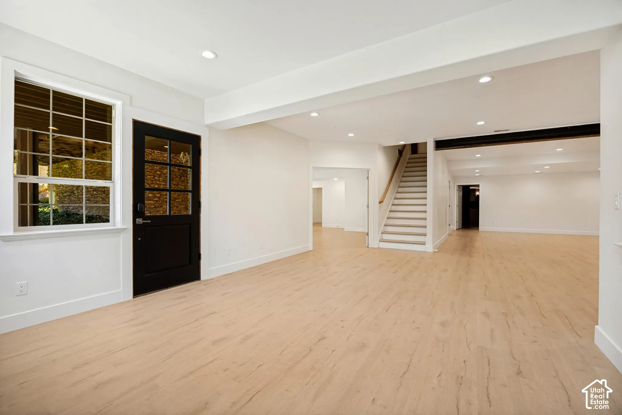 Expansive finished lower level featuring light wood-finish flooring, recessed lighting, and a window with natural light