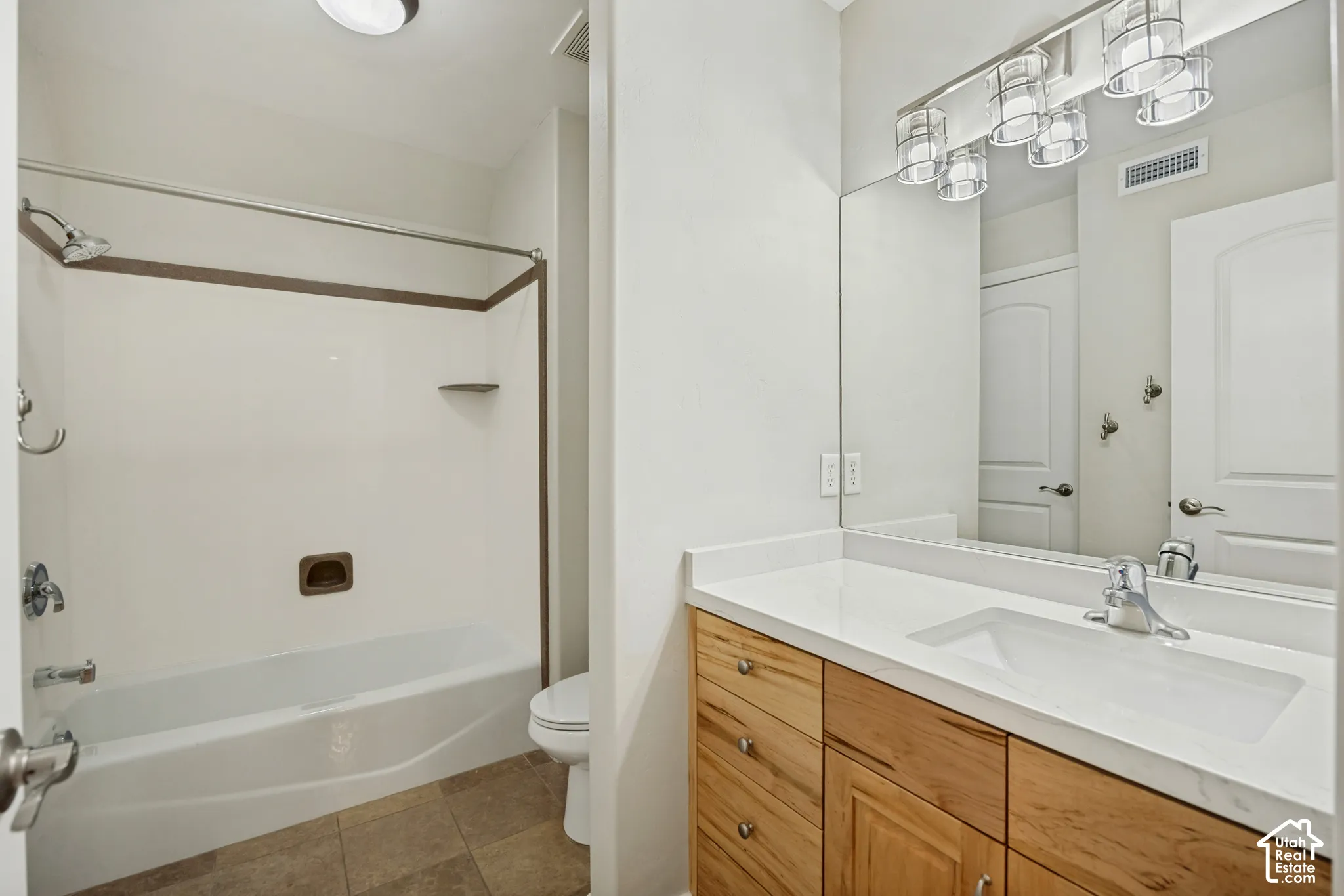 Spacious bathroom featuring a single vanity with wood-finish cabinetry, a large integrated sink, and an expansive wall-mounted mirror