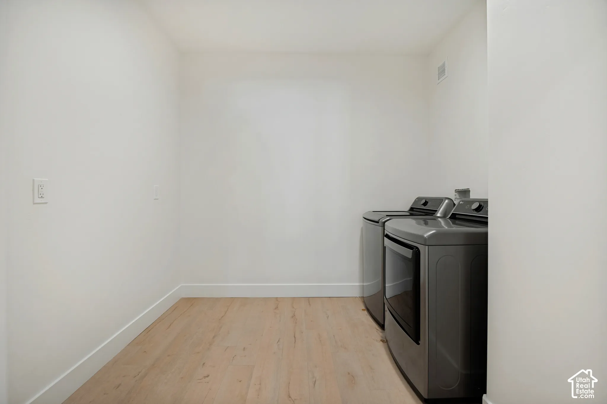 Laundry area featuring wood-finish flooring and light-toned walls