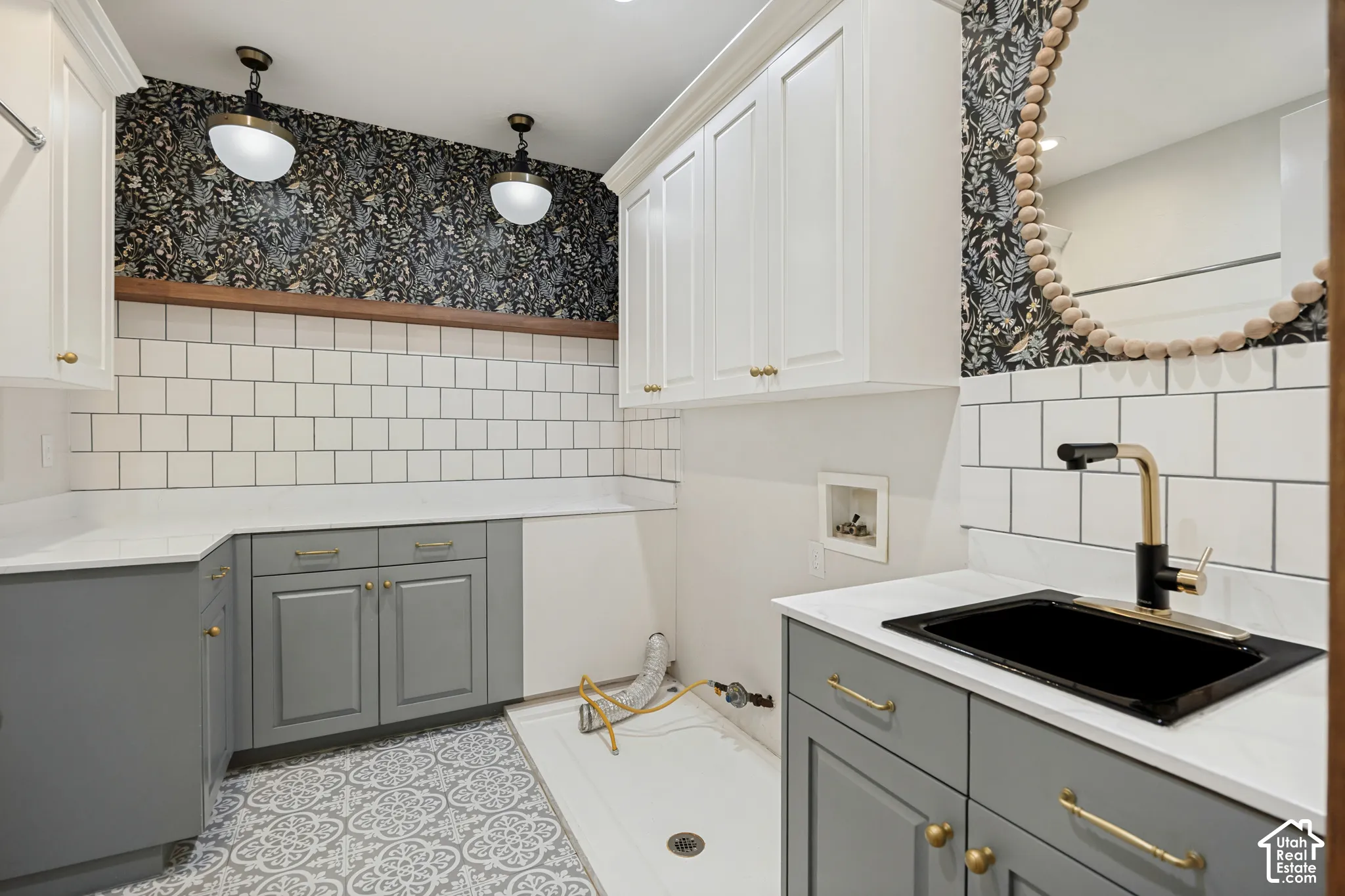White upper cabinetry, gray lower cabinetry, white subway tile backsplash, white countertops, and patterned floor tile
