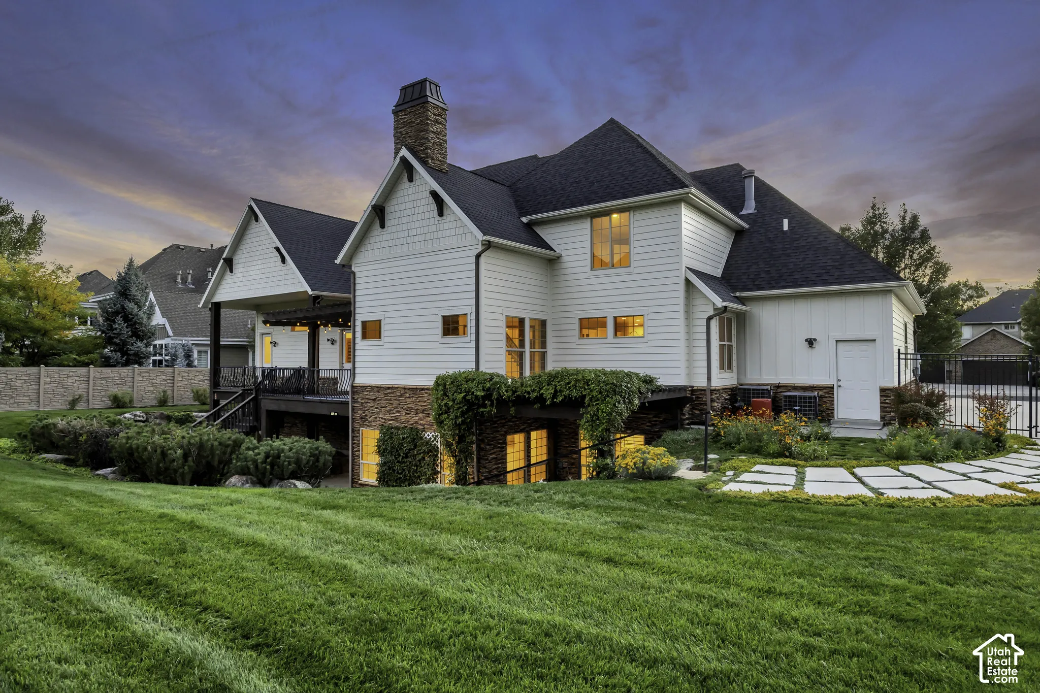 Expansive lawn with integrated patio pavers, covered porch, and exterior lighting