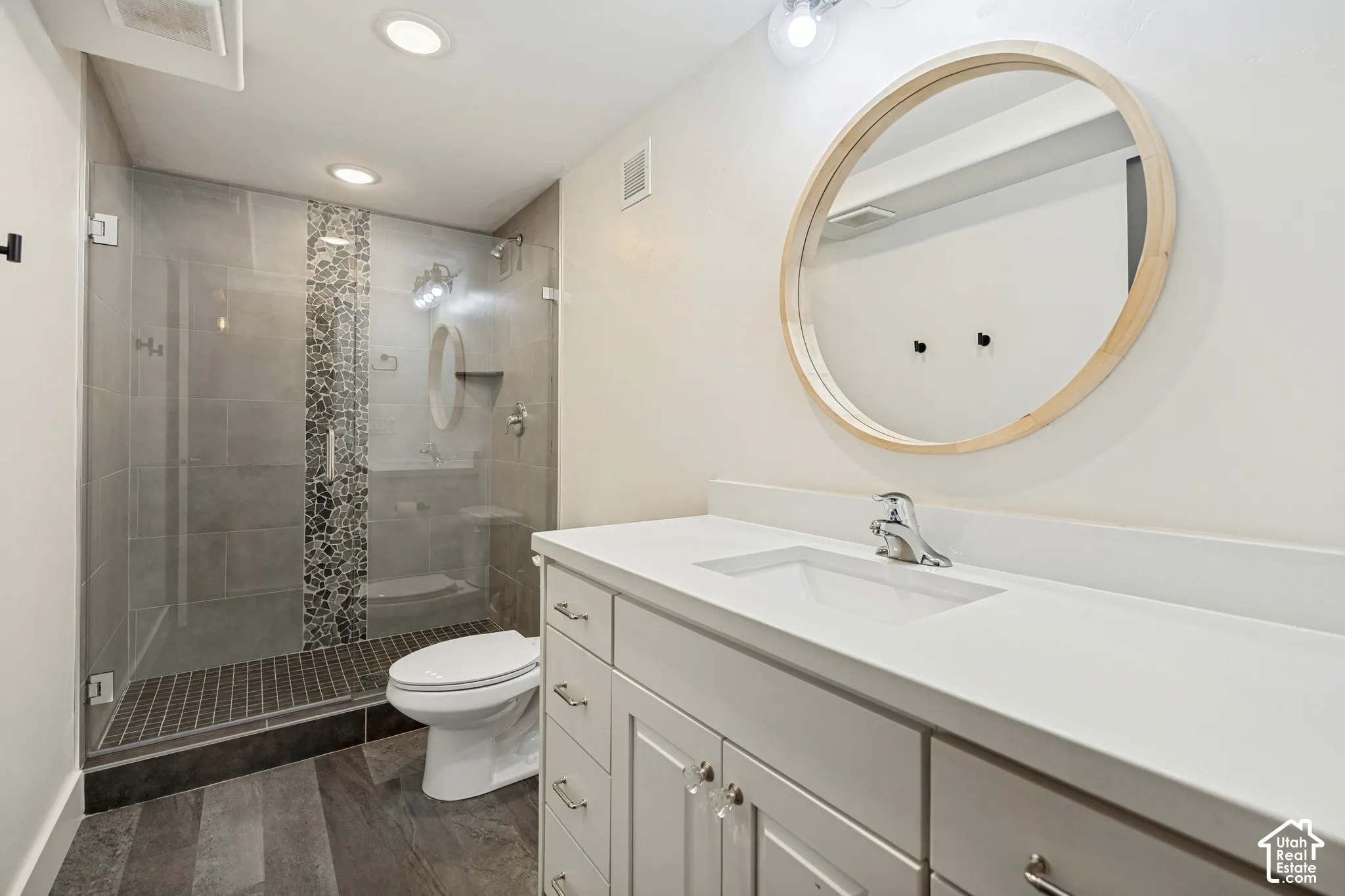 Shower featuring glass enclosure, tiled walls, and mosaic tile accent