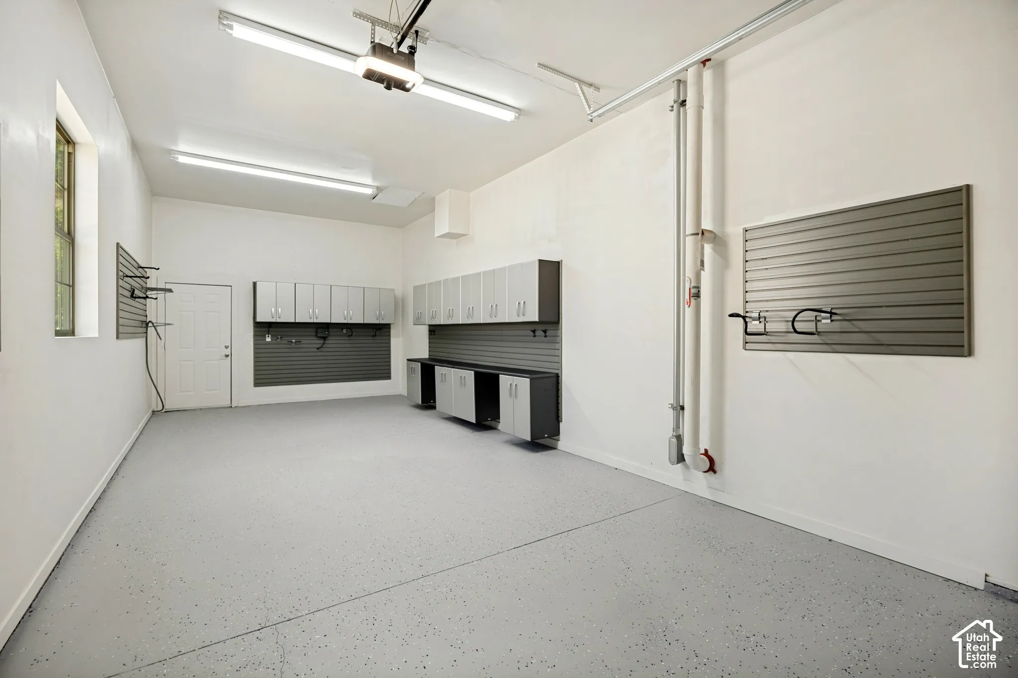 Epoxy-coated flooring, built-in cabinetry, slatted wall storage systems, and overhead fluorescent lighting fixtures