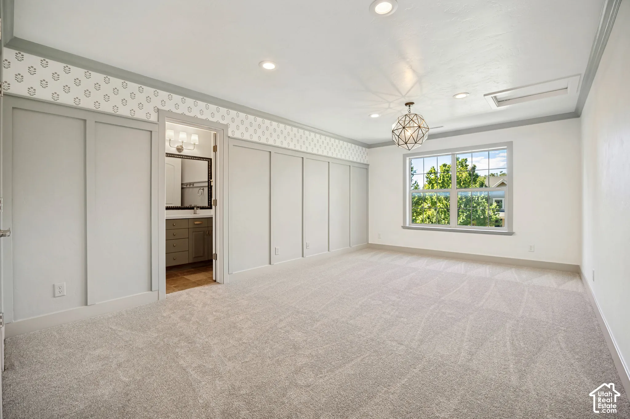 Recessed lighting, geometric chandelier, large window, board and batten wall treatment, and light-toned carpeting