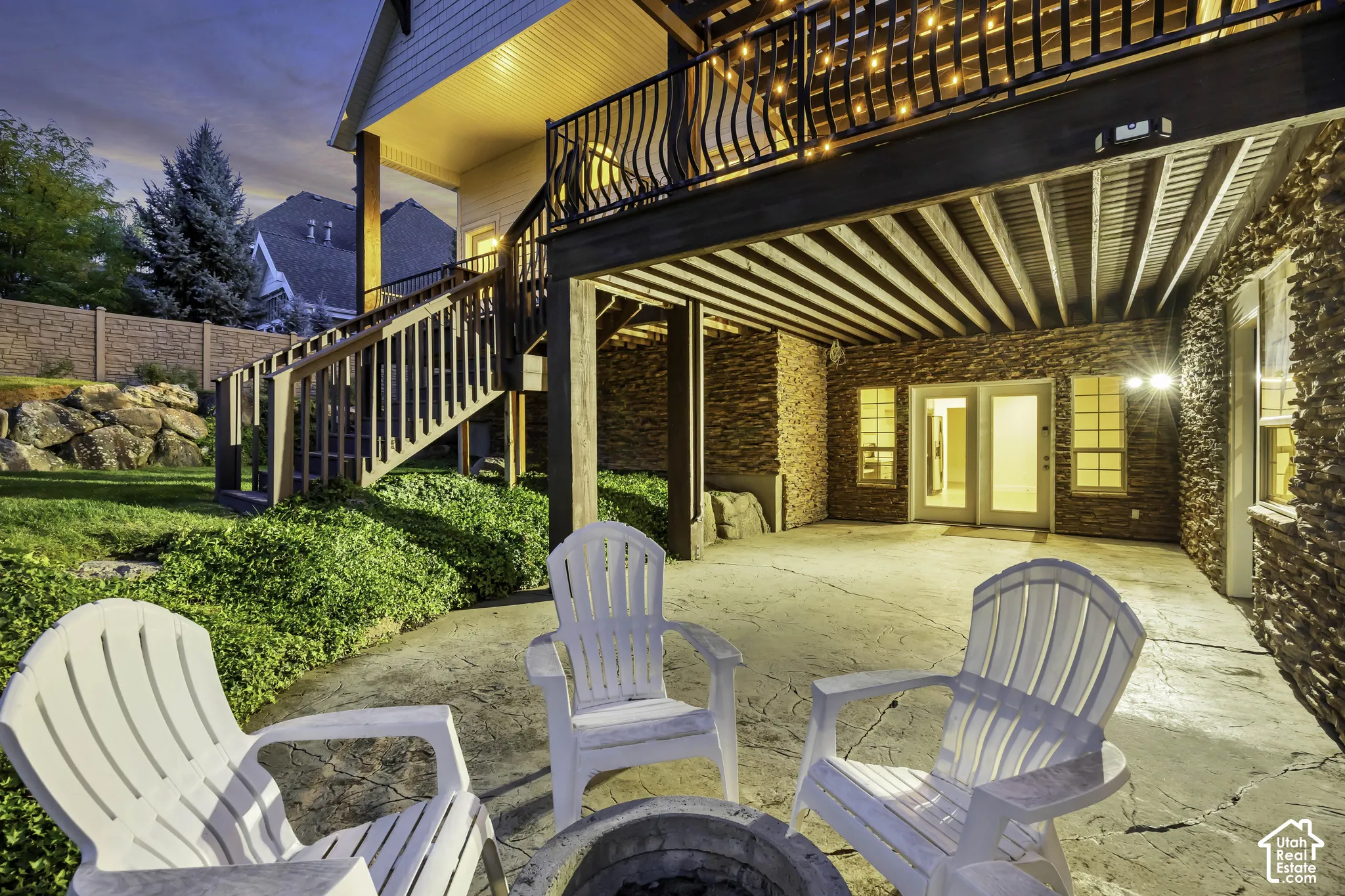 Lower-level patio with stamped concrete, stone-clad exterior, and double doors providing direct outdoor access