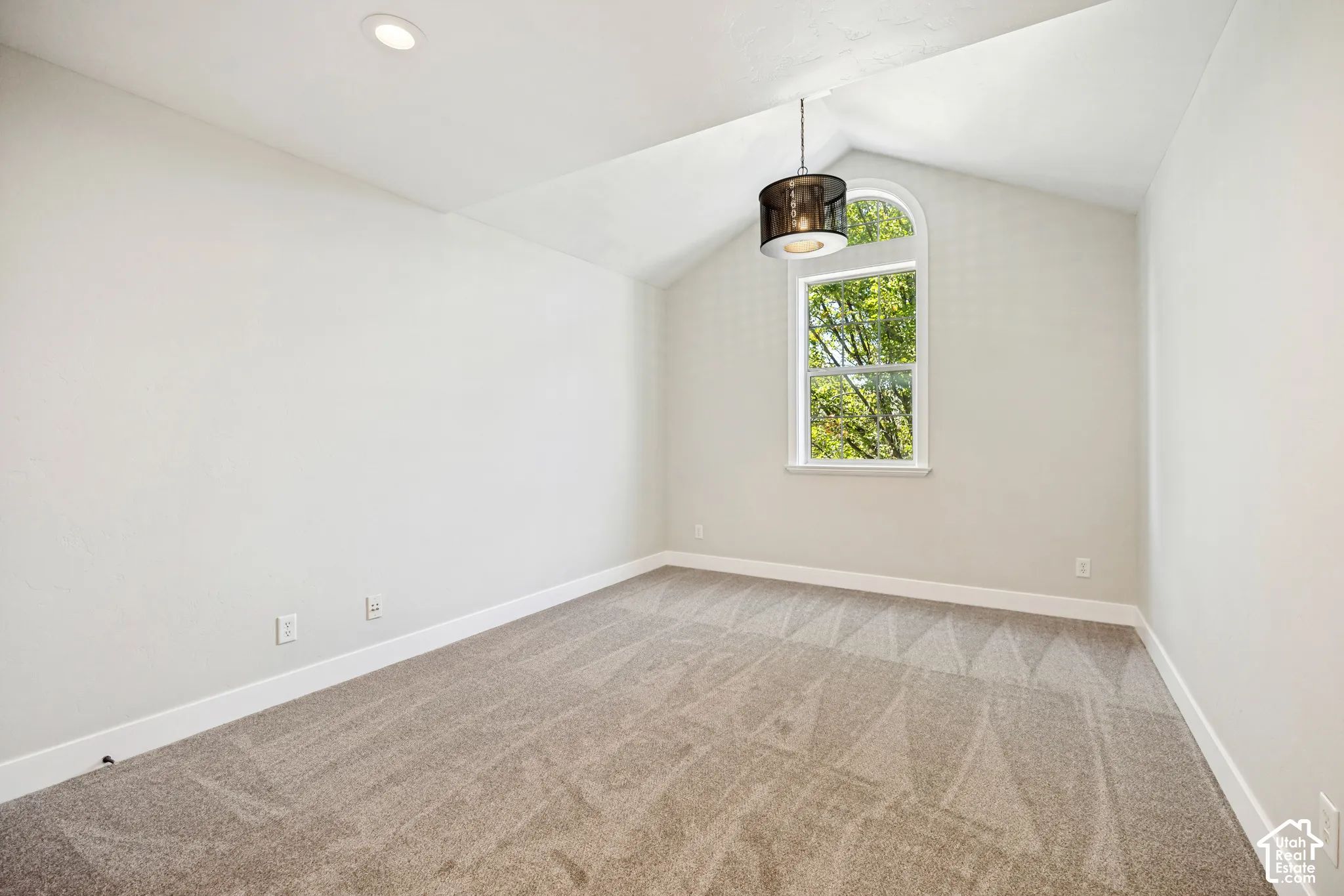 Vaulted ceiling with recessed lighting and a decorative pendant fixture