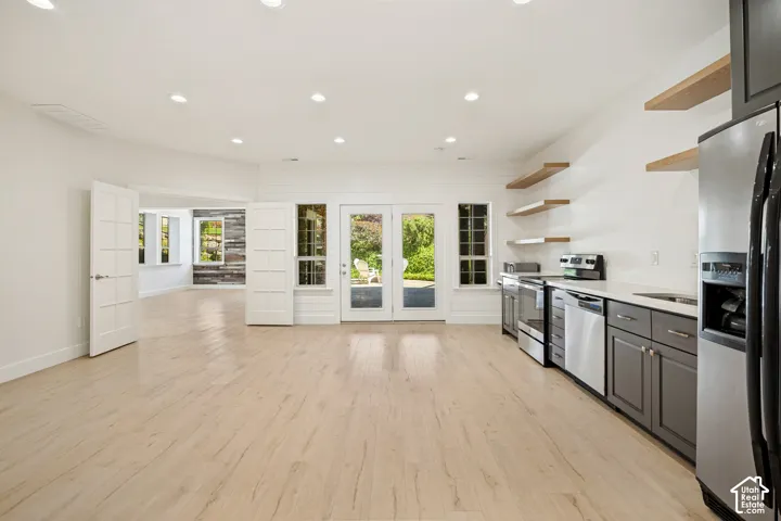 Recessed lighting, wood-finish flooring, white shiplap accent wall, stainless steel appliances, and floating wood shelves