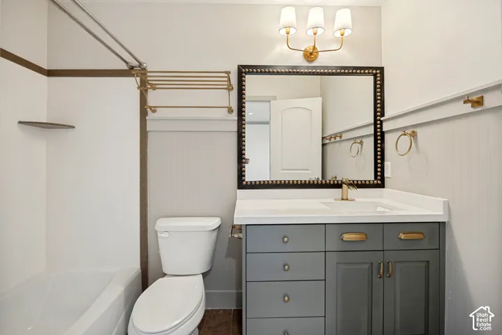 The ensuite bathroom just off the previous bedroom with tub & shower, countertop space, a single vanity with dual-tone cabinetry and gold-tone hardware, rectangular undermount sink, and wall-mounted light fixture.