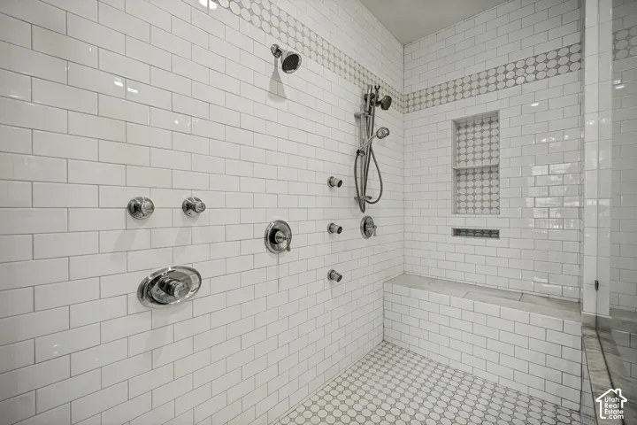 Shower featuring white subway tile, a built-in bench, recessed shelf, and multiple polished chrome fixtures