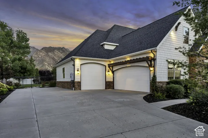 Two-car garage with arched doors, integrated pergola, and exterior lighting