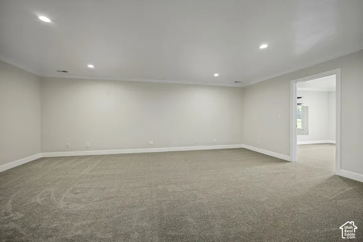 Expansive room featuring recessed lighting, crown molding, light-colored walls, and neutral carpet flooring