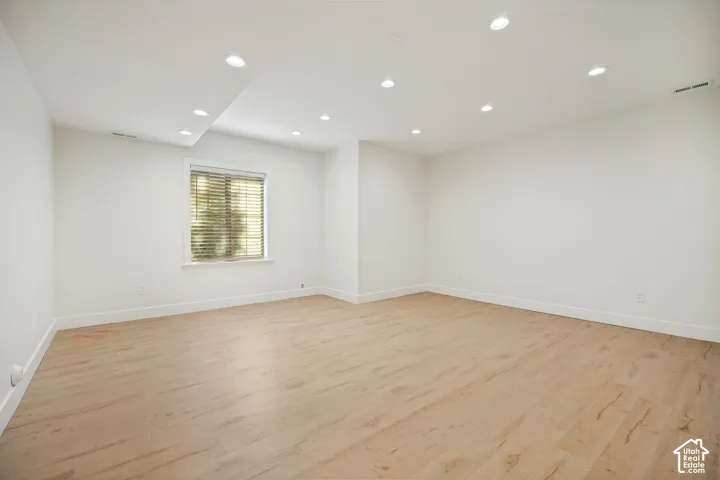 Recessed lighting illuminates the spacious room with light wood-finish flooring