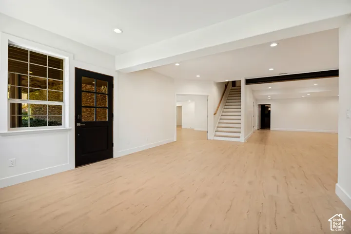 Expansive finished lower level featuring light wood-finish flooring, recessed lighting, and a window with natural light