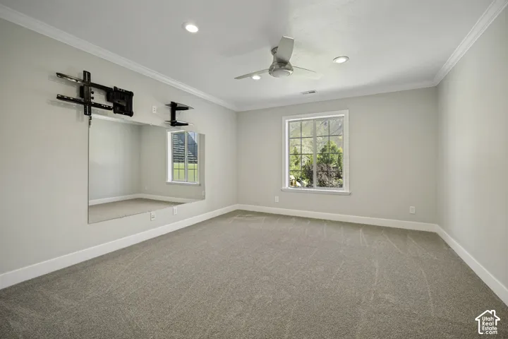 Wall-mounted mirror with built-in TV mount, recessed lighting, ceiling fan, and crown molding