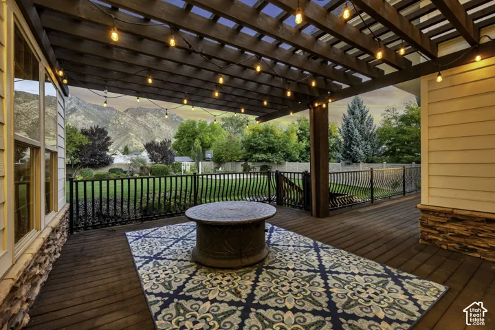 Expansive outdoor deck featuring a wooden pergola, string lighting, and mountain scenery