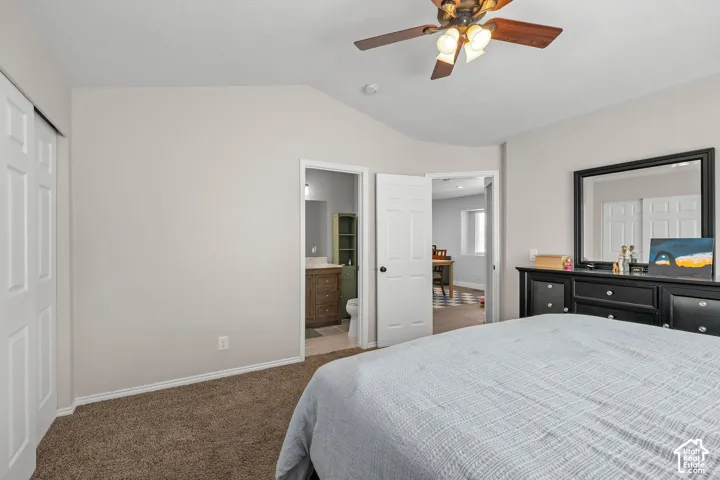 Vaulted ceiling, ceiling fan with integrated lighting, wood-finish flooring in the adjacent room, white paneled doors, and brown carpeting