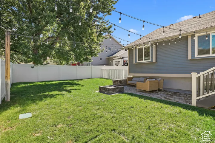 Expansive green lawn, white privacy fencing, and a built-in fire pit