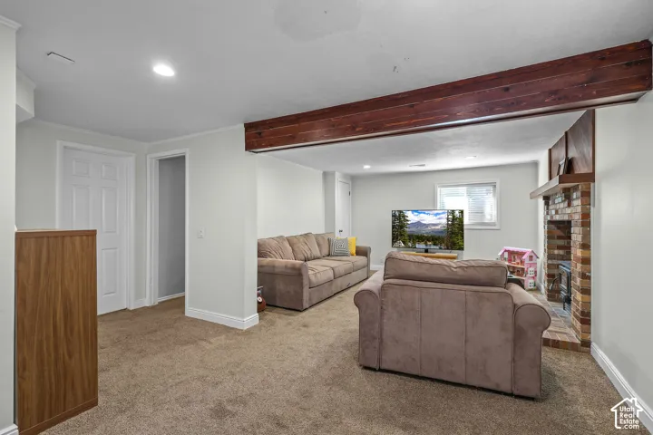 Carpeted interior space featuring a wood beam, recessed lighting, and a brick fireplace