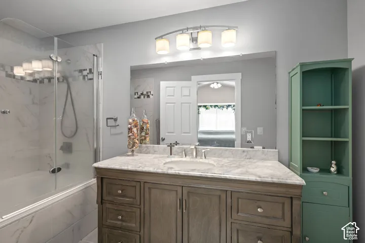 Vanity with a light-toned countertop, integrated sink, and an undermount faucet