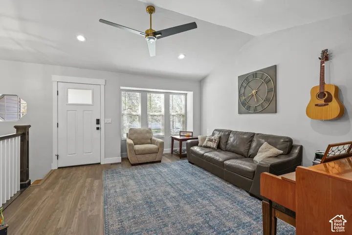 Wood-finish flooring, vaulted ceiling with a modern ceiling fan, recessed lighting, and a bay window
