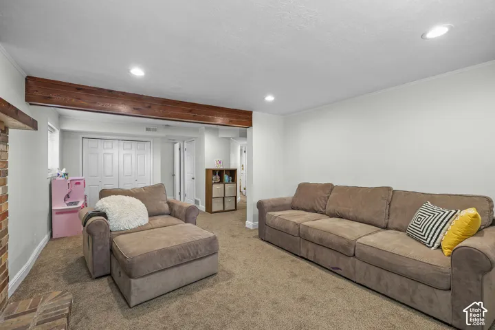 Recessed lighting, exposed wood beam, brick hearth, carpeted flooring, and white bi-fold doors