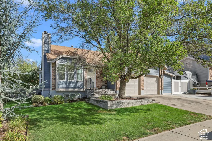 Property exterior featuring a brick chimney, bay window, two-car garage, and a retaining wall