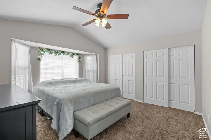 Vaulted ceiling, ceiling fan with light fixture, bay window with blinds, dual sliding closet doors, and plush carpeting
