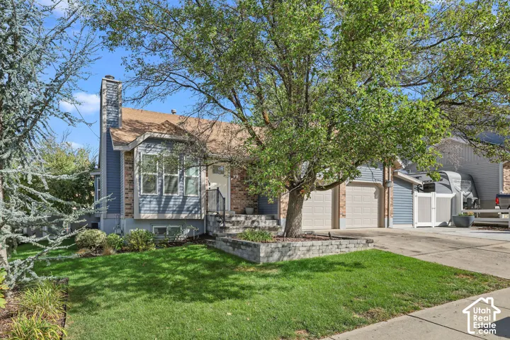 Property exterior featuring a brick chimney, bay window, two-car garage, and a retaining wall