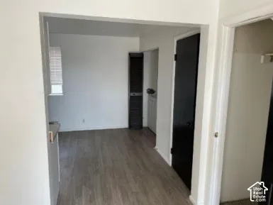 Wood-finish flooring, white walls, and a window with blinds