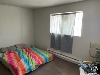 Carpeted flooring, neutral wall tones, window with natural light, and a baseboard heater
