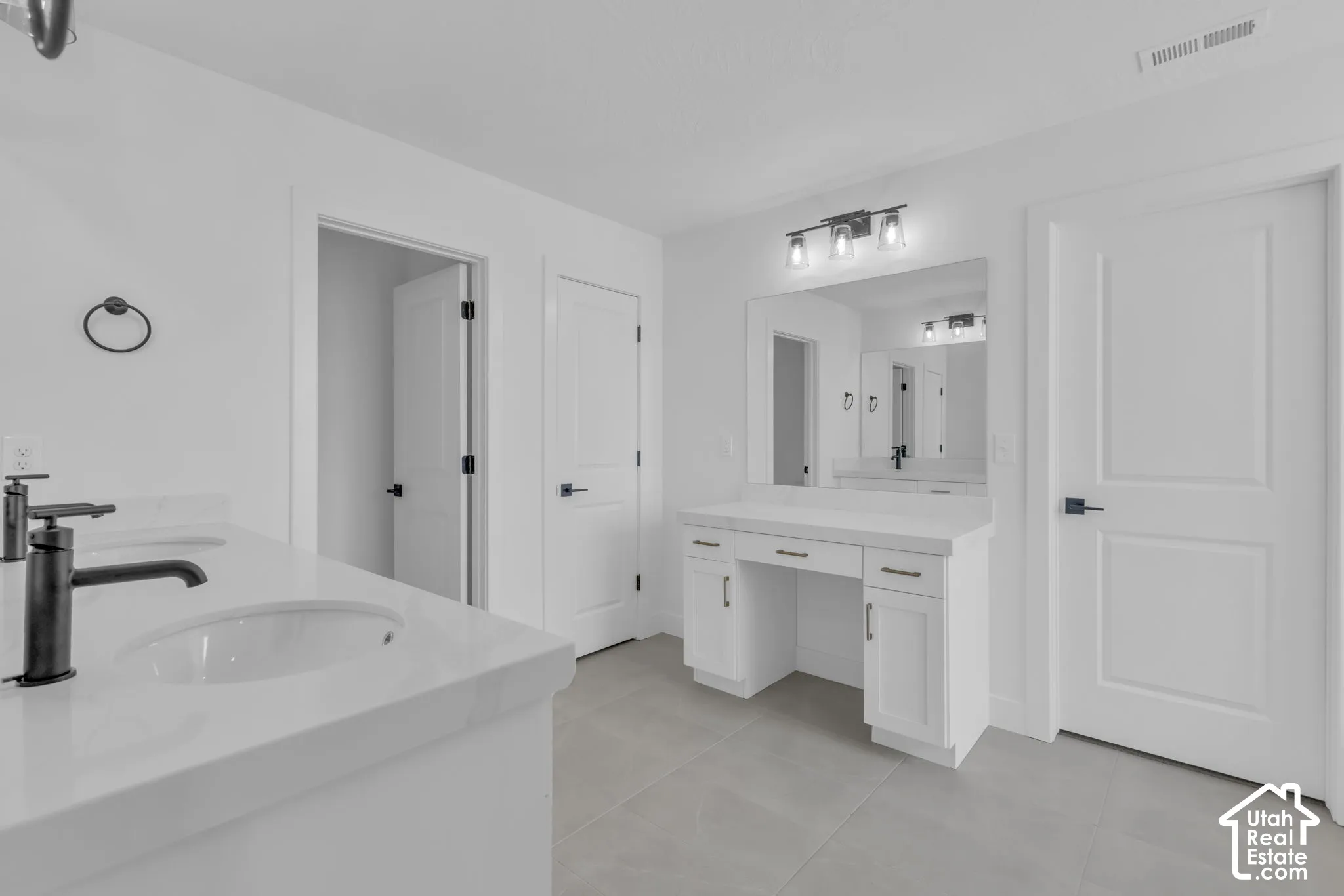 Primary bath with custom cabinetry, matte black hardware, dual vanity with undermount sinks, and a built-in makeup vanity.