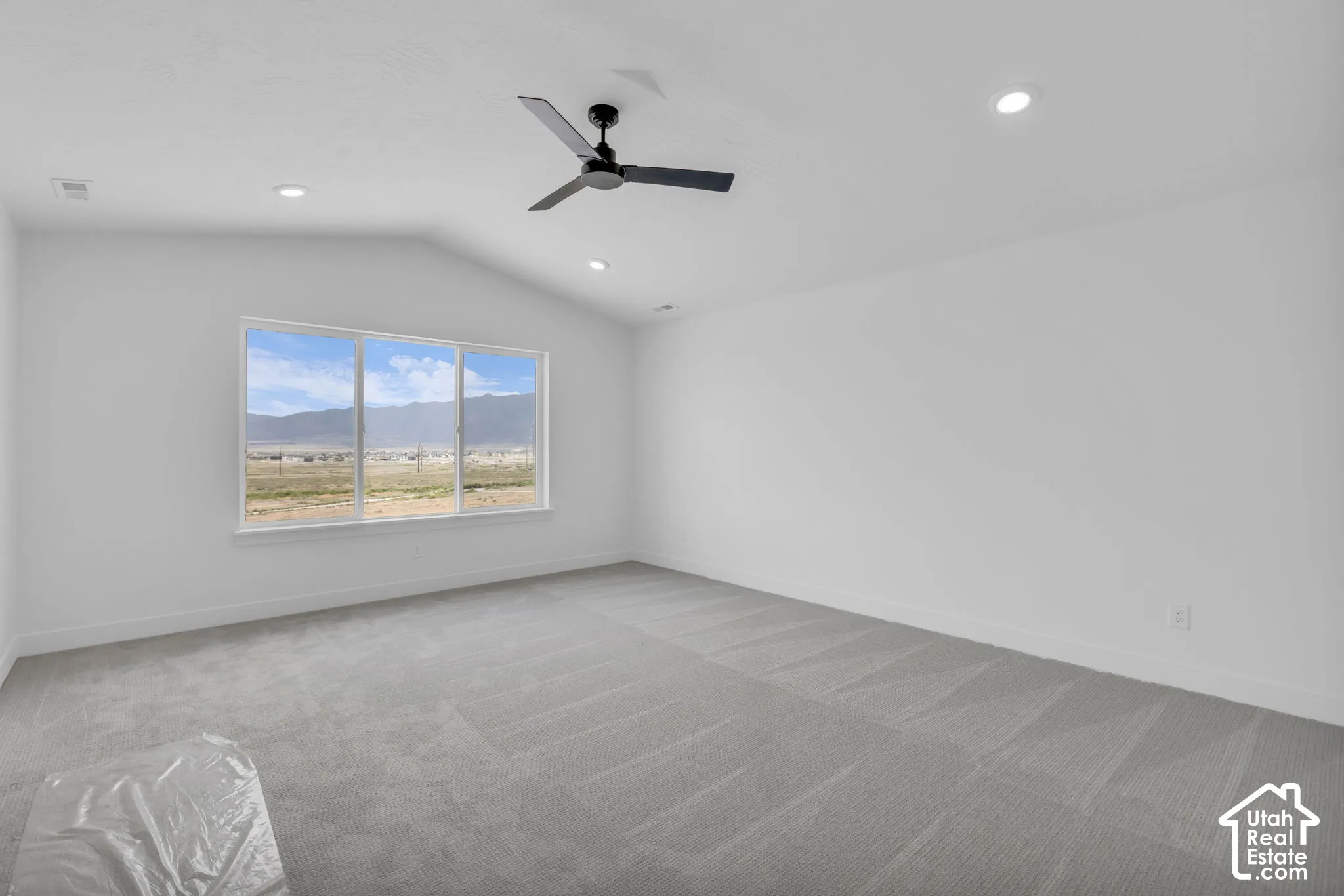 Primary bedroom with vaulted ceiling featuring a contemporary ceiling fan, large custom windows with spectacular mountain views.