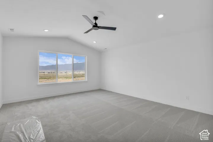 Primary bedroom with vaulted ceiling featuring a contemporary ceiling fan and large custom windows with spectacular mountain views.