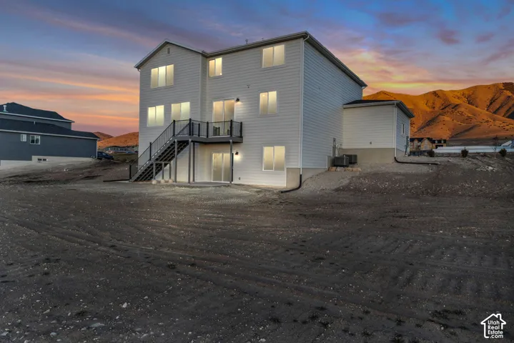 Back of home from the southwest corner showing second-story deck, black railing, and exterior staircase.  Home includes a walkout basement to a flat backyard on a .75 acre lot.