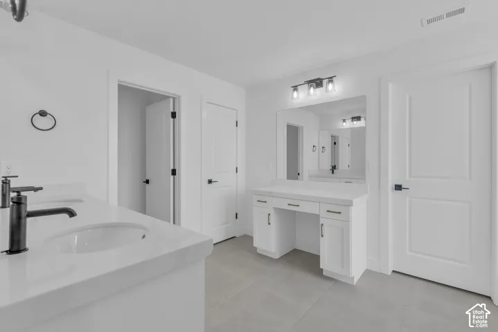 Primary bath with custom cabinetry, matte black hardware, dual vanity with undermount sinks, and a built-in makeup vanity.