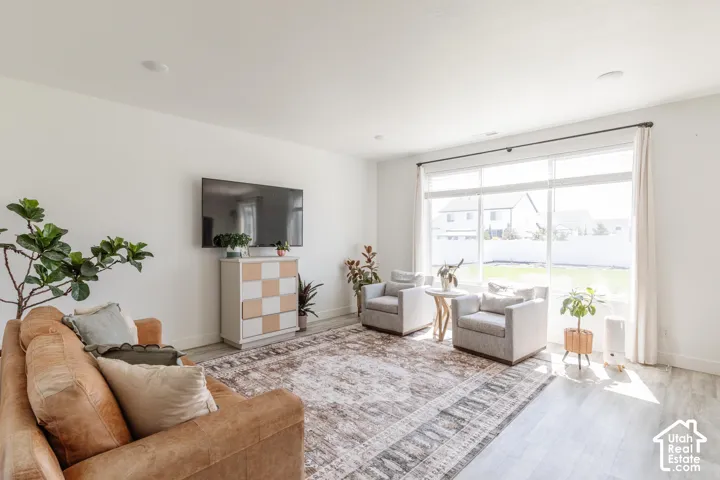 Recessed lighting, light wood-finish flooring, a full wall of windows with roller shades, and a checkered console cabinet