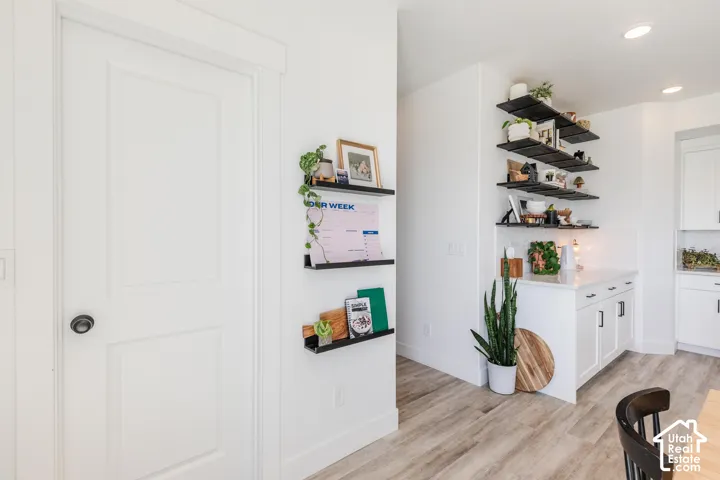Wood-finish flooring, white paneled door, built-in shelving, white cabinetry, and a white countertop