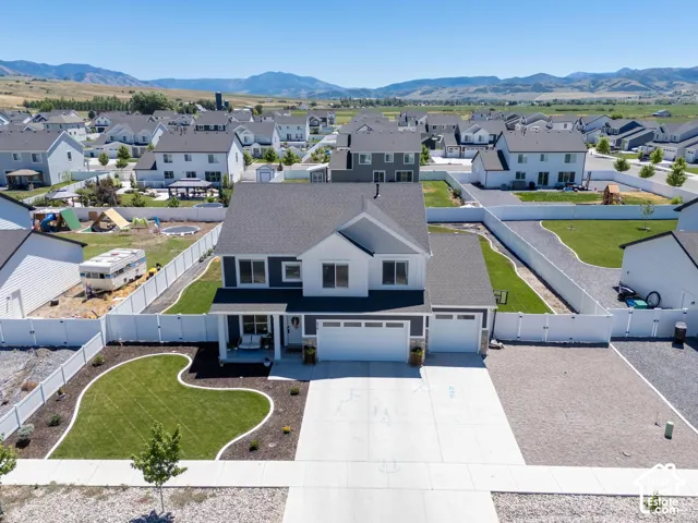 Contemporary two-story exterior with a contrasting dark and light facade, attached two-car garage, white privacy fencing, and a manicured front lawn