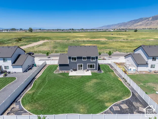 Expansive backyard featuring a manicured lawn, concrete patio, and white privacy fencing