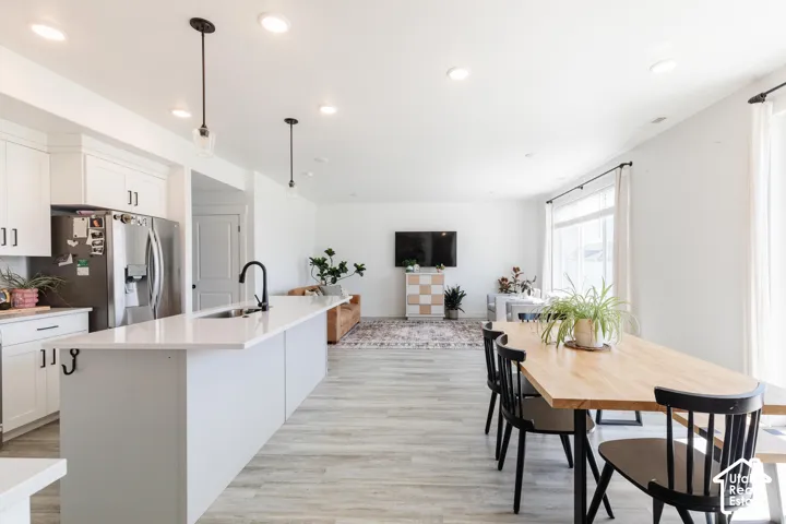 Kitchen featuring stainless steel appliances, white cabinetry, and a large island with a sink and matte black faucet