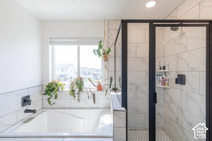 Soaking tub with a matte black faucet, surrounded by large format tile